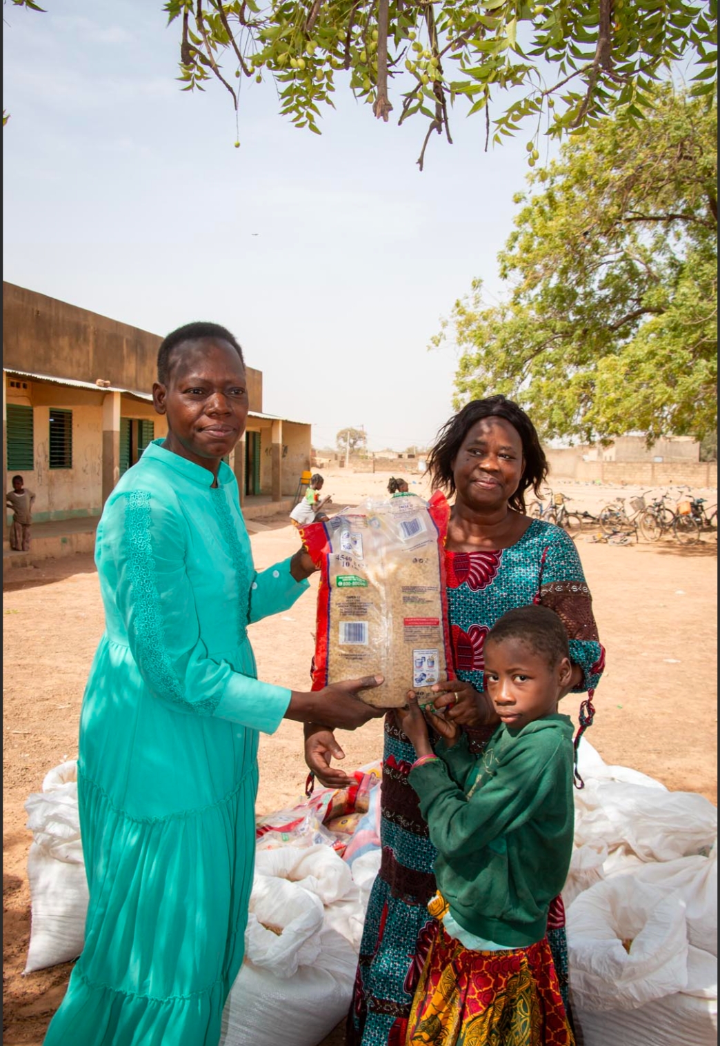A volunteer handing a backpack to a smiling child during a community distribution
